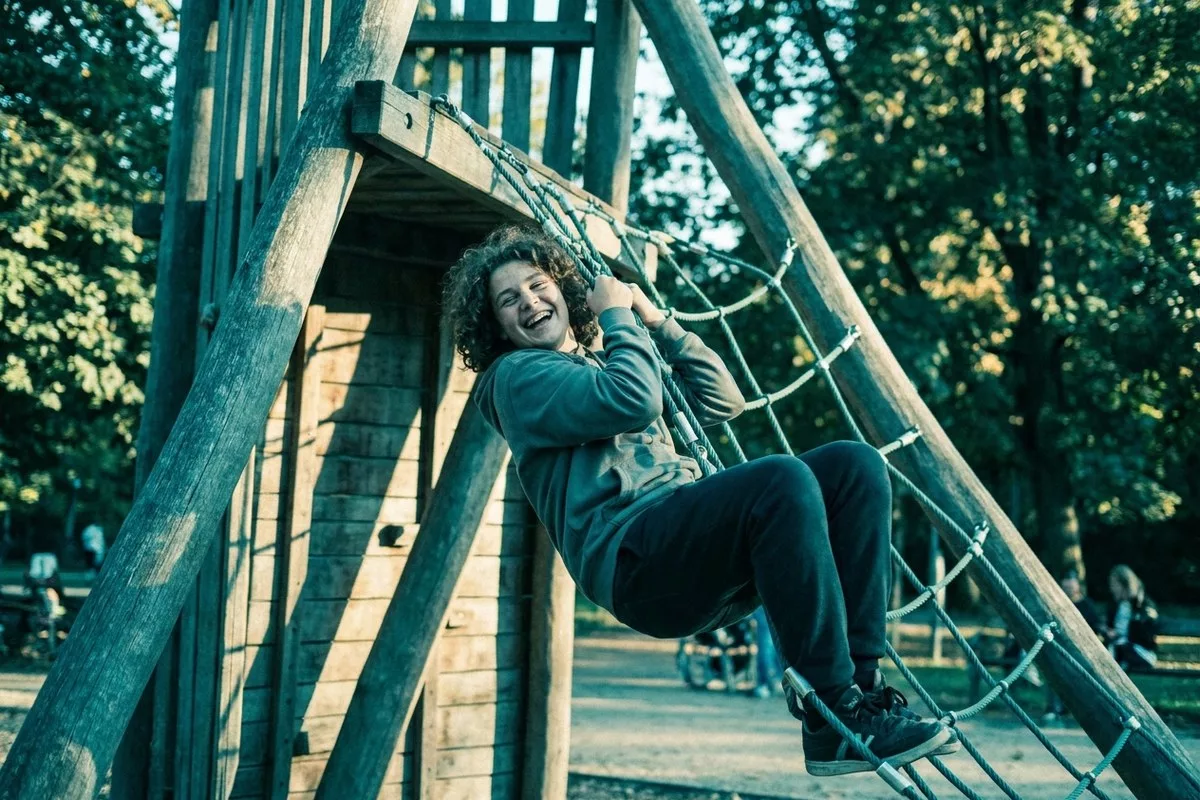 Ein übergewichtiger Teenager klettert fröhlich und voller Energie auf einem Spielgerät im Park