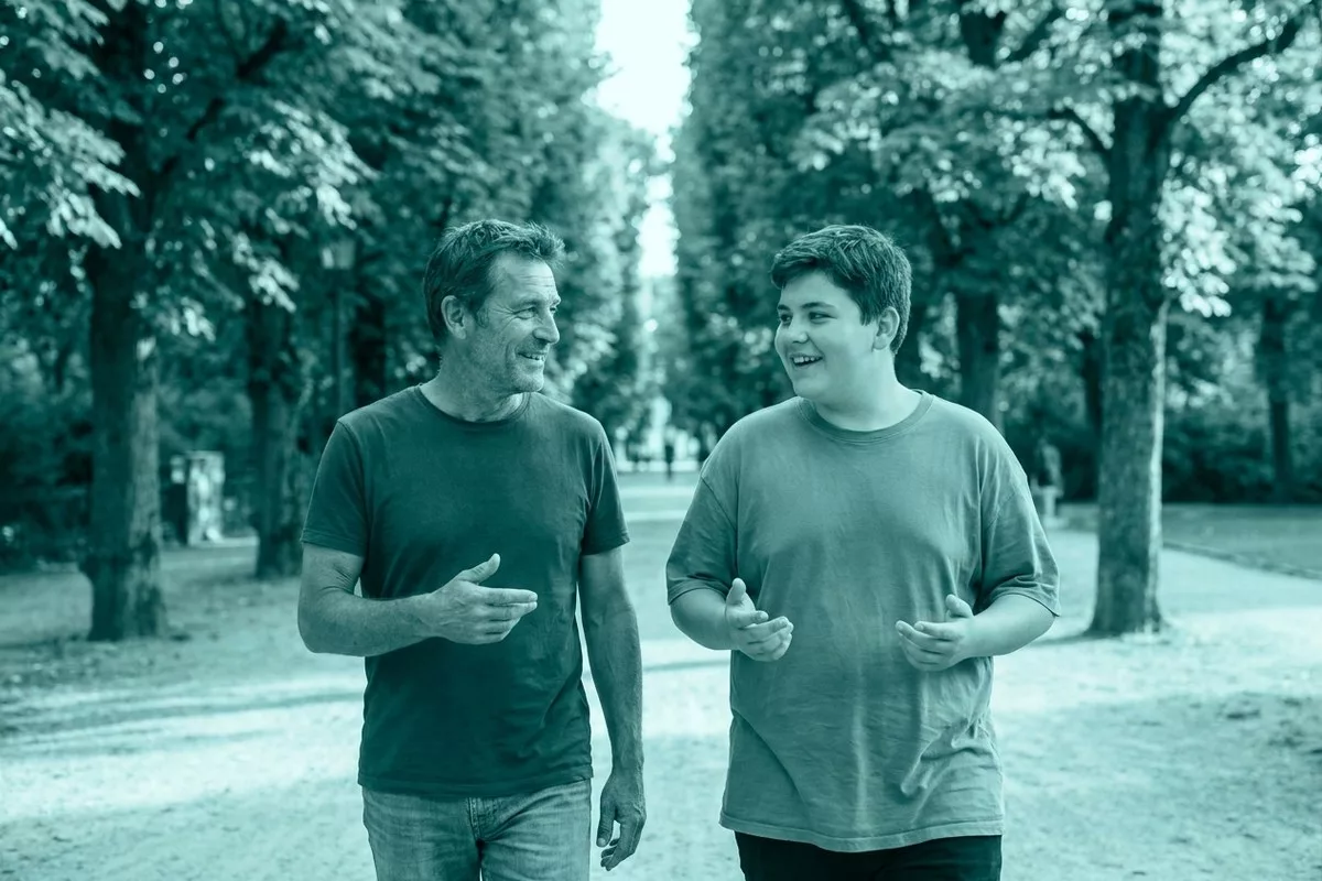 Ein Vater spaziert entspannt mit seinem Teenager-Sohn durch einen Park